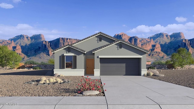 single story home featuring concrete driveway, a mountain view, an attached garage, and stucco siding