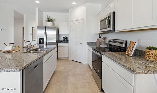 kitchen with white cabinets, stainless steel appliances, a sink, and an island with sink