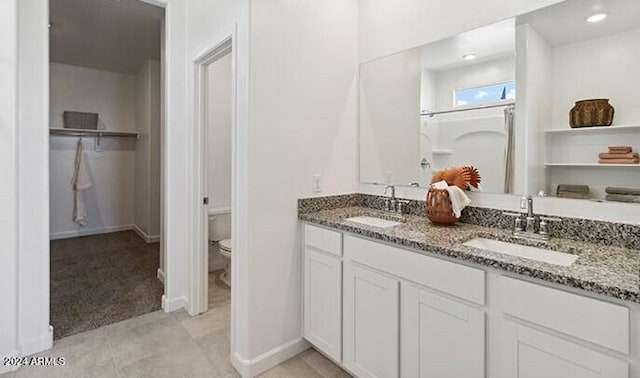 bathroom featuring recessed lighting, a sink, toilet, and double vanity