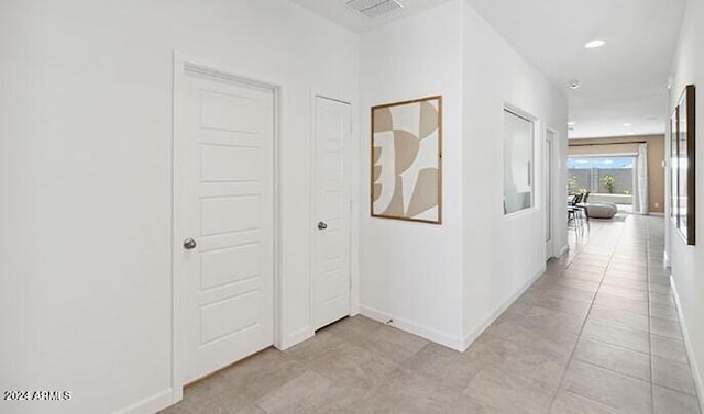 corridor featuring light tile patterned floors, recessed lighting, visible vents, and baseboards