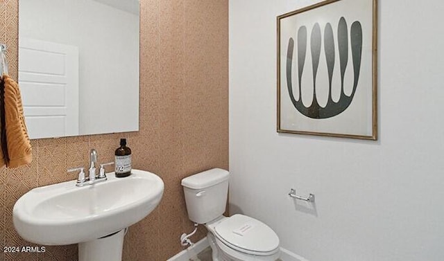 half bath featuring baseboards, a sink, and toilet