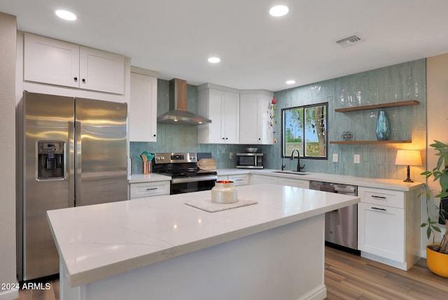 kitchen featuring sink, stainless steel appliances, white cabinetry, and wall chimney range hood