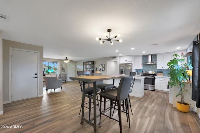 dining space featuring light hardwood / wood-style flooring and ceiling fan with notable chandelier