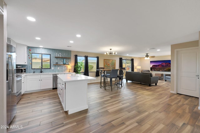 kitchen featuring a kitchen island, light wood-type flooring, white cabinetry, and appliances with stainless steel finishes