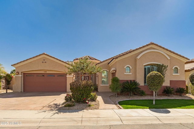 mediterranean / spanish house with driveway, an attached garage, a tiled roof, and stucco siding