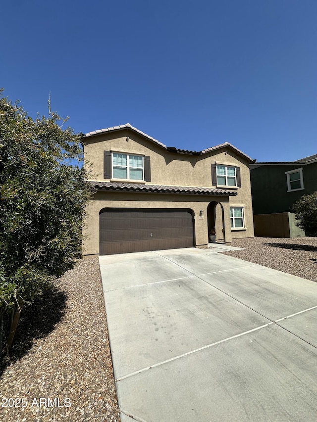 view of front of home featuring concrete driveway, a tiled roof, a garage, and stucco siding