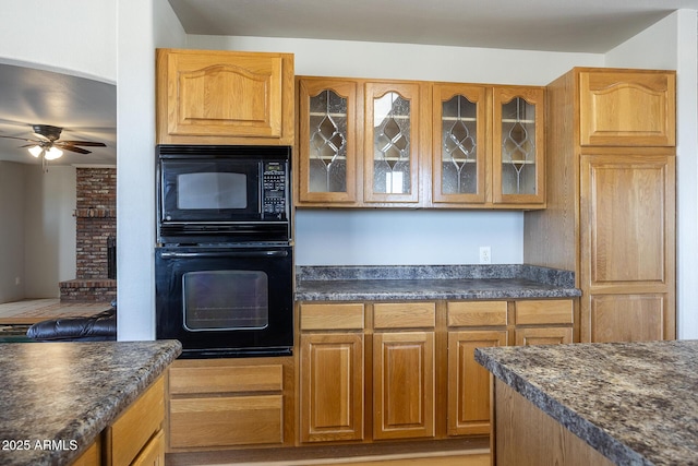 kitchen with black appliances, a ceiling fan, glass insert cabinets, and brown cabinets