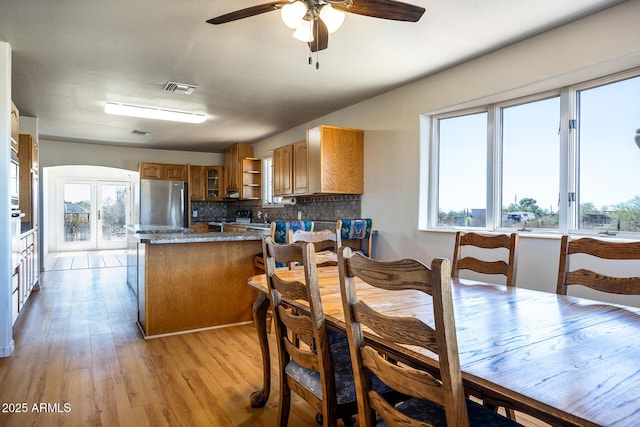 kitchen with visible vents, glass insert cabinets, brown cabinets, freestanding refrigerator, and a peninsula