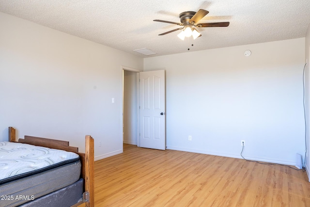 bedroom featuring visible vents, baseboards, a ceiling fan, a textured ceiling, and light wood-style floors