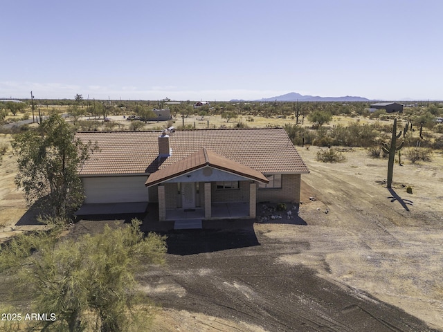 view of front of house featuring a tile roof, a rural view, a patio area, a mountain view, and brick siding