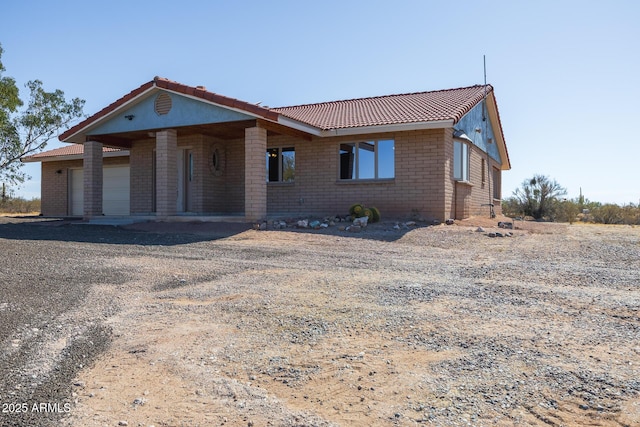 view of front of home with a garage, a tile roof, and brick siding