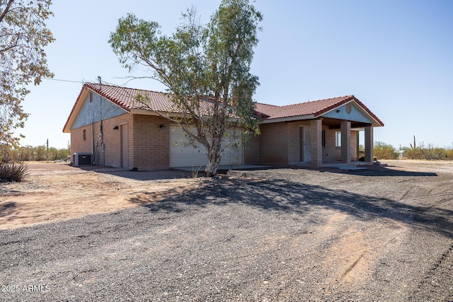 view of front of property with a garage, central air condition unit, and a tiled roof