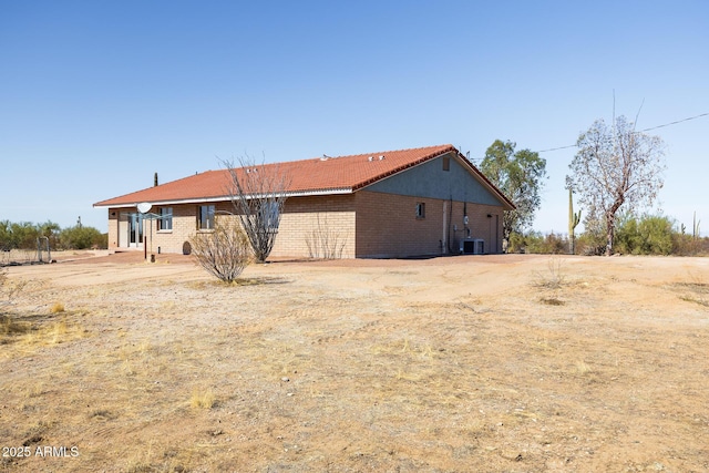 back of property with cooling unit and brick siding