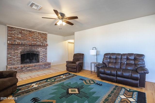 living room with light wood finished floors, a fireplace, visible vents, and baseboards