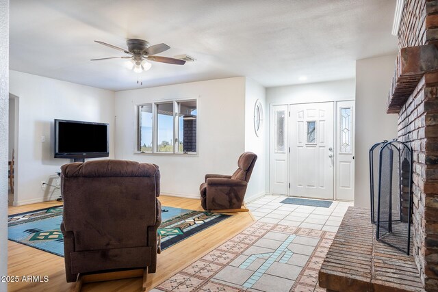 foyer entrance with a fireplace, ceiling fan, baseboards, and wood finished floors