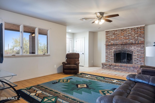 living room with visible vents, baseboards, a ceiling fan, wood finished floors, and a brick fireplace