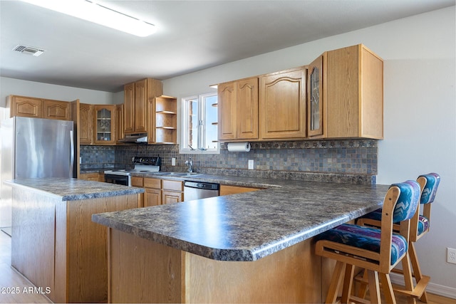 kitchen with glass insert cabinets, dark countertops, stainless steel appliances, and a peninsula