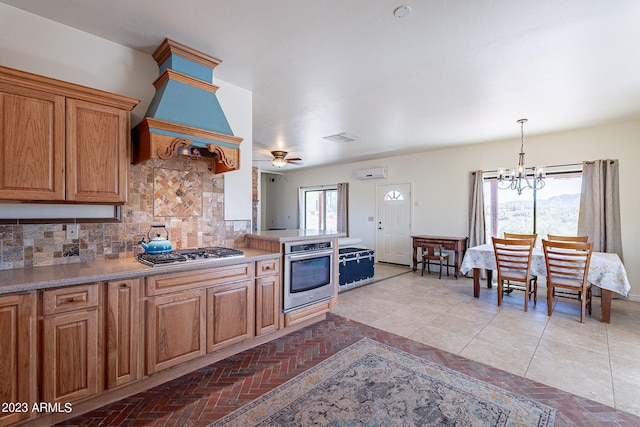 kitchen featuring ceiling fan with notable chandelier, backsplash, stainless steel appliances, and plenty of natural light