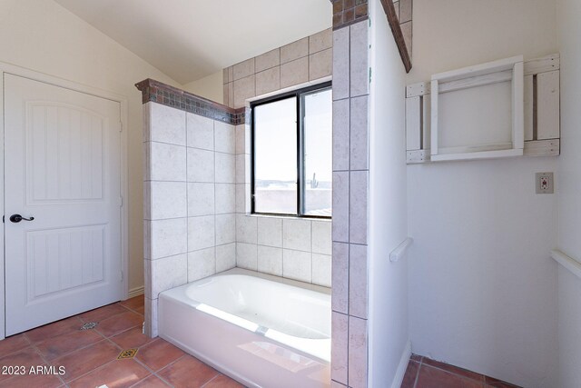 bathroom with tile patterned flooring, vaulted ceiling, and a tub