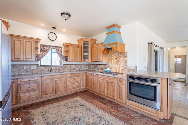 kitchen featuring kitchen peninsula, stainless steel appliances, tasteful backsplash, and sink