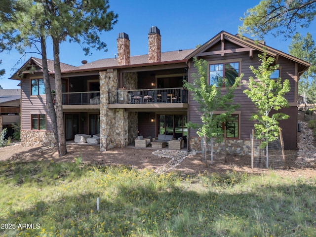 rear view of property featuring an outdoor living space, a balcony, and a patio area