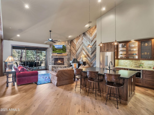 bar featuring pendant lighting, stainless steel appliances, a fireplace, and light hardwood / wood-style flooring