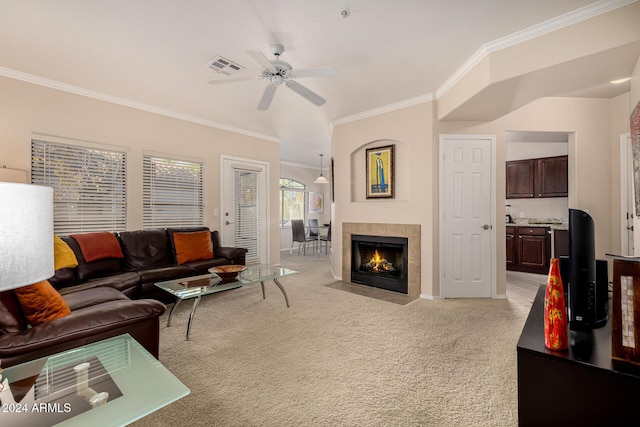 living room featuring ceiling fan, light colored carpet, ornamental molding, and a tiled fireplace