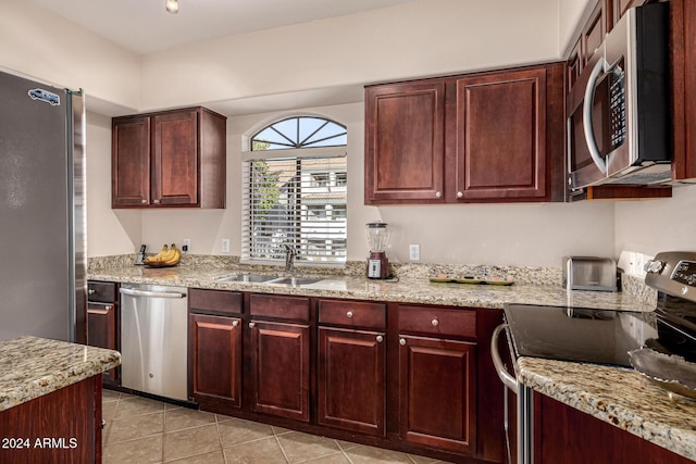 kitchen featuring light tile patterned flooring, sink, light stone countertops, and stainless steel appliances