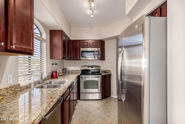 kitchen featuring light tile patterned flooring, stainless steel appliances, light stone counters, and sink