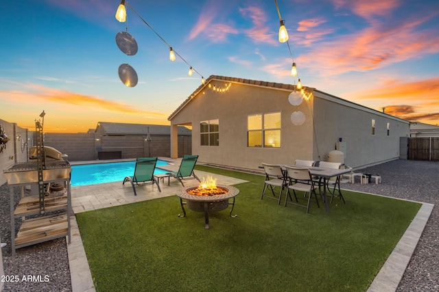 exterior space featuring an outdoor fire pit, stucco siding, a fenced backyard, a patio, and a yard