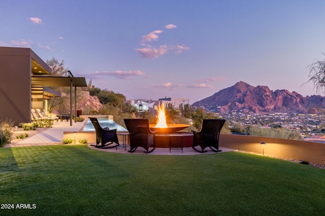 yard at dusk with a mountain view, an outdoor fire pit, and a patio