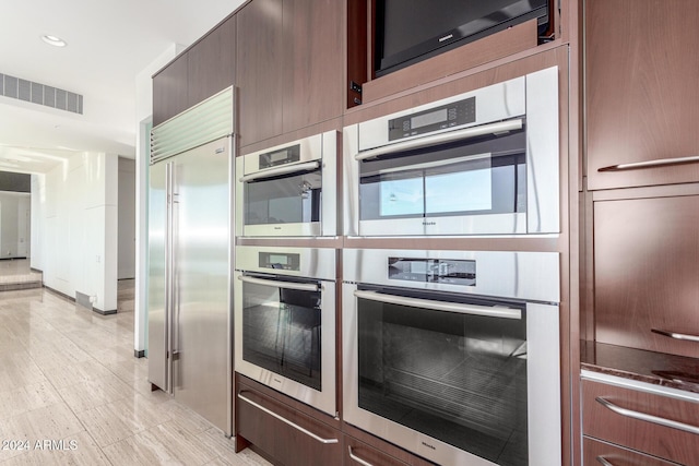 kitchen featuring built in appliances and dark brown cabinets