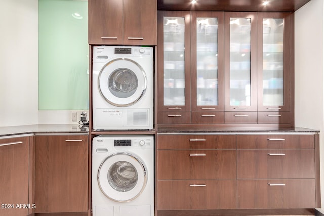 laundry room featuring stacked washer / dryer and cabinets