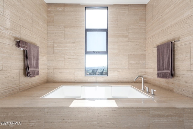 bathroom with a relaxing tiled tub and tile walls