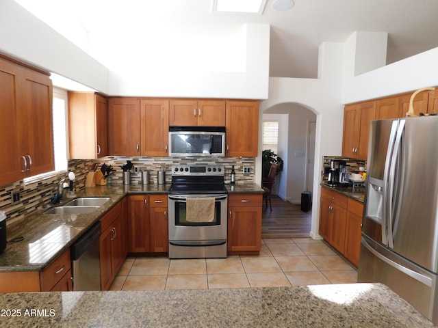 kitchen with dark stone counters, sink, tasteful backsplash, light tile patterned flooring, and stainless steel appliances