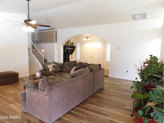 living room featuring hardwood / wood-style floors, ceiling fan with notable chandelier, and vaulted ceiling