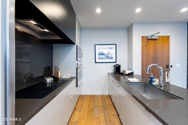 kitchen with sink, ventilation hood, light hardwood / wood-style flooring, black electric cooktop, and white cabinets