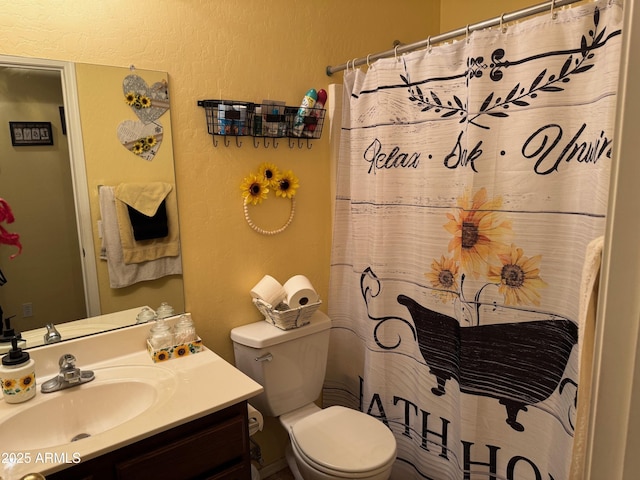 bathroom with toilet, vanity, a shower with shower curtain, and a textured wall