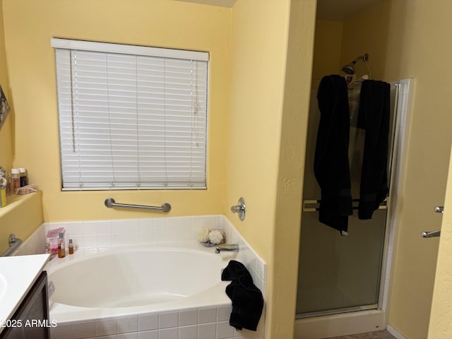 bathroom with a stall shower, vanity, and a bath