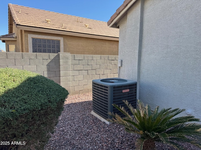 details with stucco siding, cooling unit, a tile roof, and fence