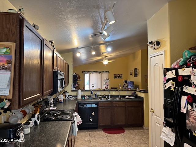 kitchen featuring a sink, black appliances, vaulted ceiling, a textured ceiling, and dark countertops