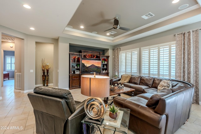 living room with light tile patterned floors, a tray ceiling, ceiling fan, and a healthy amount of sunlight