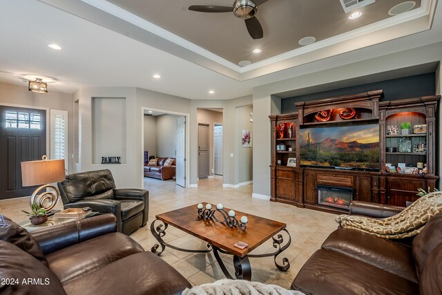 living room with ceiling fan, ornamental molding, and a tray ceiling