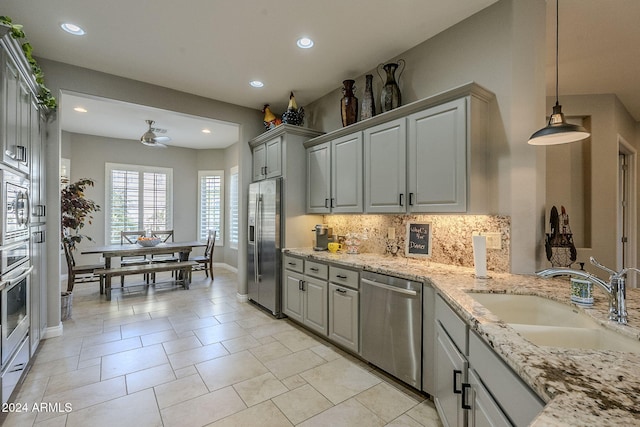 kitchen with appliances with stainless steel finishes, tasteful backsplash, gray cabinetry, ceiling fan, and sink