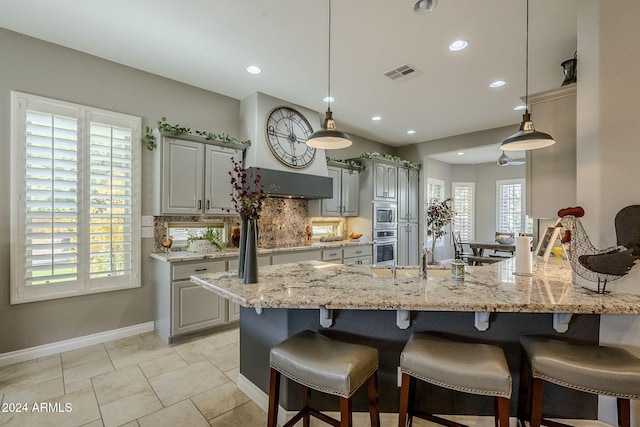 kitchen with backsplash, gray cabinetry, and kitchen peninsula