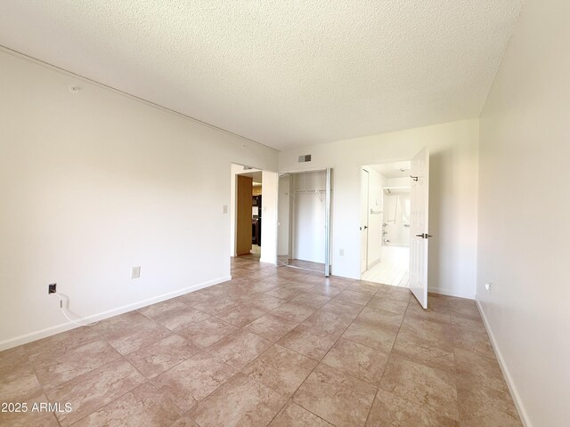 10330 W Thunderbird Blvd Unit C304, Sun City, AZ 85351 - unfurnished bedroom featuring a textured ceiling, a closet, ensuite bath, and baseboards