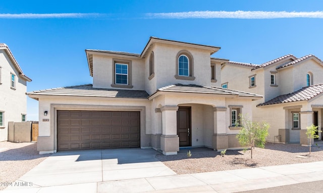 mediterranean / spanish house featuring stucco siding, concrete driveway, an attached garage, and a tile roof