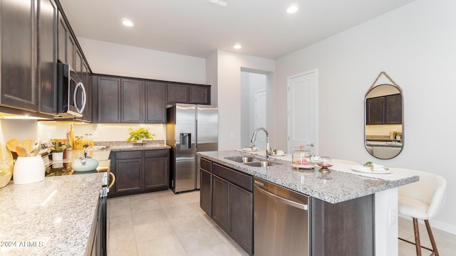 kitchen with a sink, stainless steel appliances, dark brown cabinets, and an island with sink