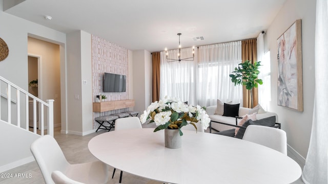 dining area with baseboards, an accent wall, a chandelier, and stairs