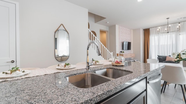 kitchen featuring decorative light fixtures, open floor plan, light stone counters, an inviting chandelier, and a sink